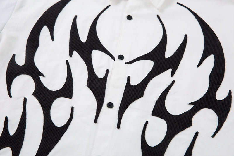 Close-up of white shirt front with black tribal flame graphic and buttons