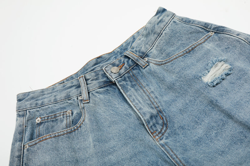 Angled close-up of front waist on light blue wide-leg denim shorts with ripped knee detail