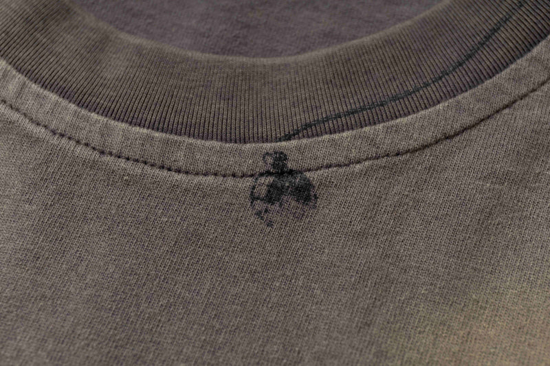 Close-up of a washed vintage tee collar with faded abstract sketch print and textured brown fabric
