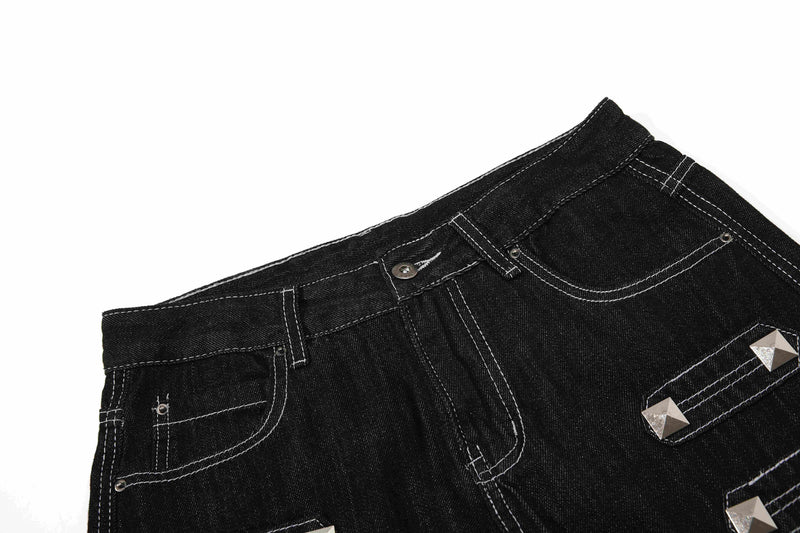 Close-up of black denim waistband and front pocket with studded strap detail