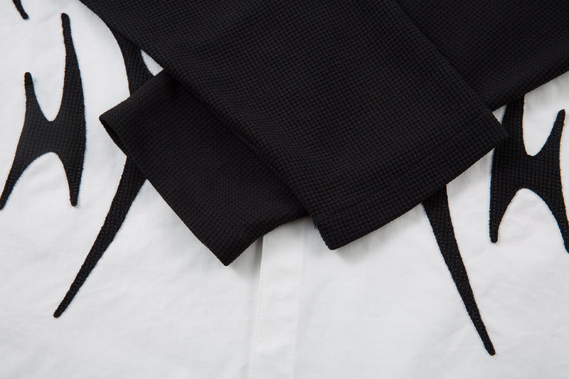 Black layered long sleeve over white shirt front, close-up of cuff and hem overlap