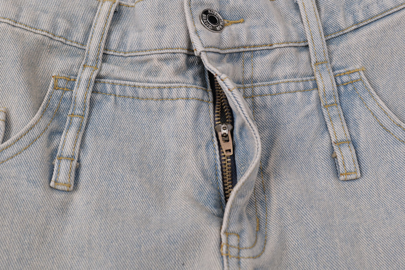 Close-up of jeans front fly with metal zipper, button, belt loops, and topstitching