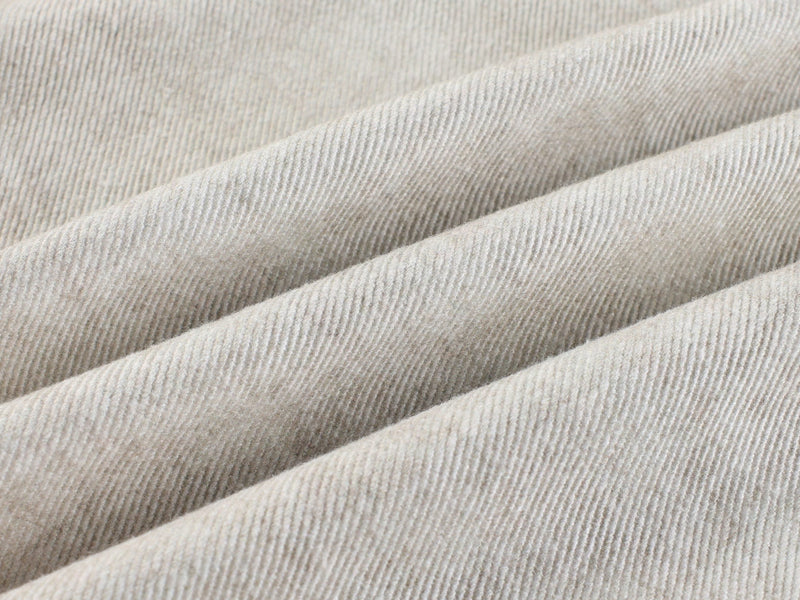 Close-up of cream corduroy-like fabric texture with soft diagonal folds