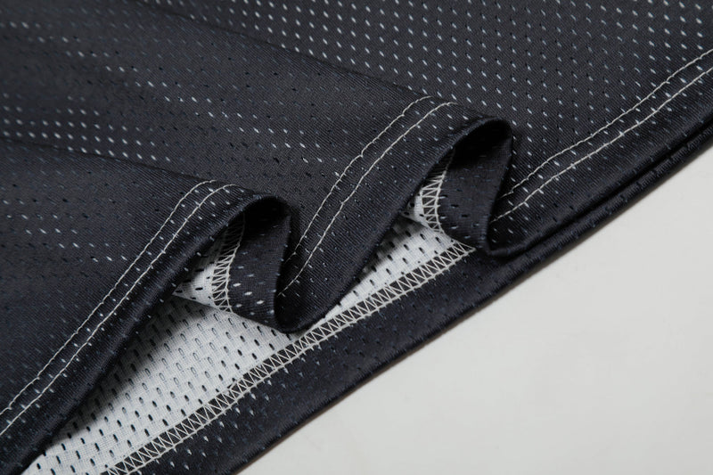 Close-up of black tech mesh jersey fabric with visible white stitching and perforated lining detailing