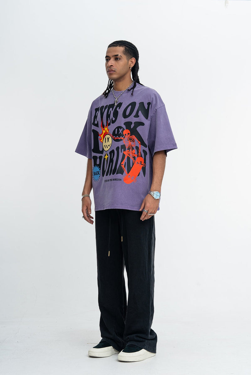 Model wearing a vintage wash purple oversized skate graphic tee with bold skeleton and horizon print
