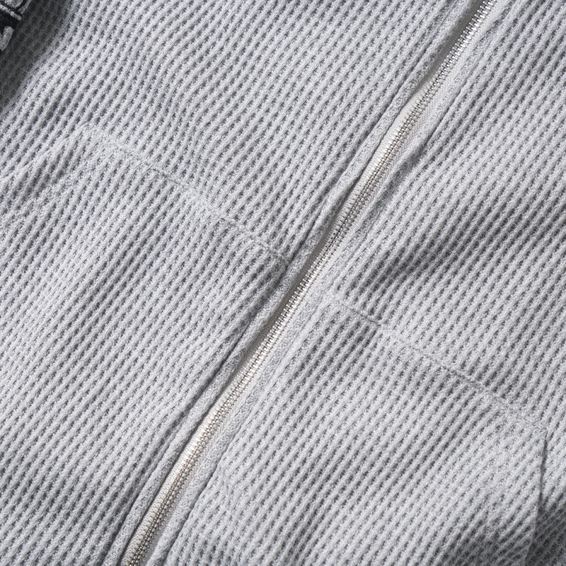 Close-up of the front zipper and waffle knit texture on the gray hoodie