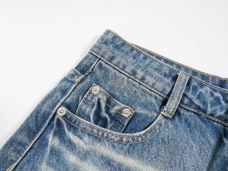 Angled close-up of the front pocket and waistband on washed denim shorts