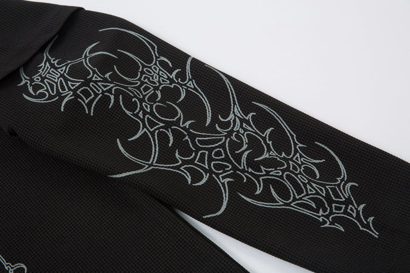 Close-up of black sleeve showing large gray barbed ornament graphic