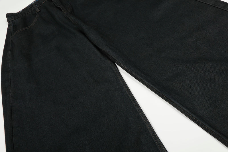 Wide-leg black denim pants laid flat with one leg crossed over the other