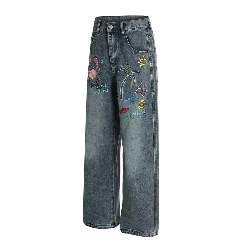 Angled front view of blue wide-leg denim jeans with tropical embroidery and relaxed fit