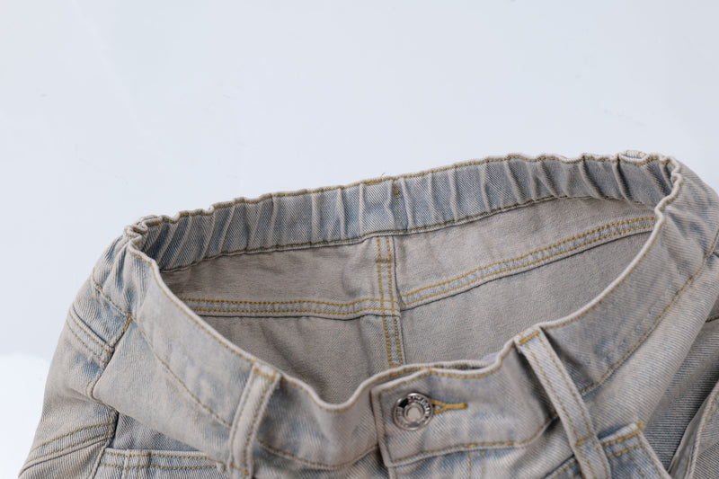 Close-up of elastic back waistband on light wash jeans with button closure and inner lining