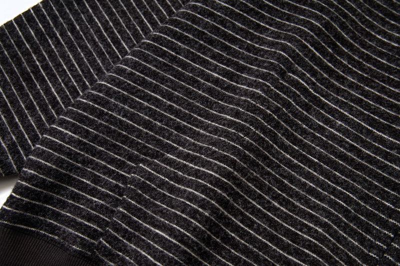 Close-up of black striped knit sleeve and shoulder with thin white stripes