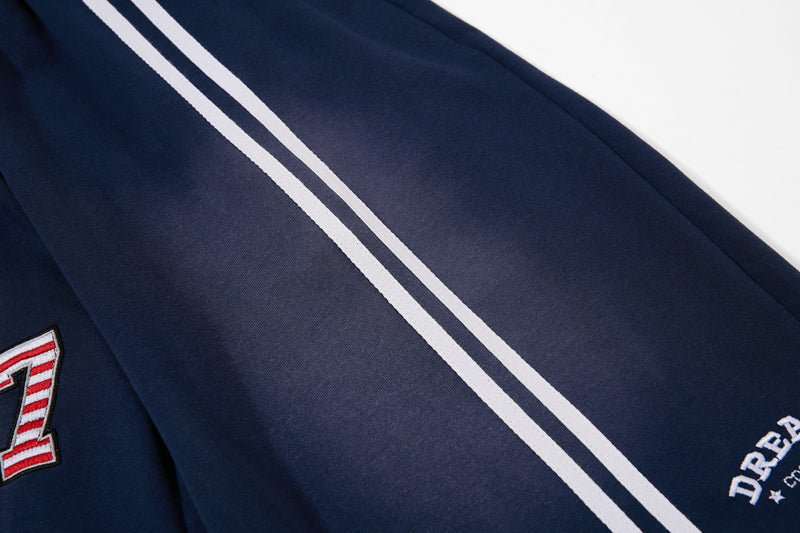 Close-up of white side stripes and lower leg on navy athletic shorts
