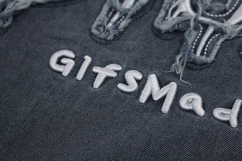 Close-up of a vintage washed denim-style T-shirt with distressed star patches and raised embroidered lettering