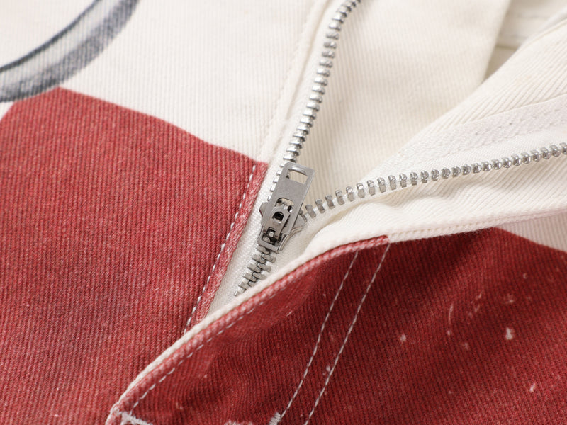 Close-up of zipper fly opening on cream and red printed jeans