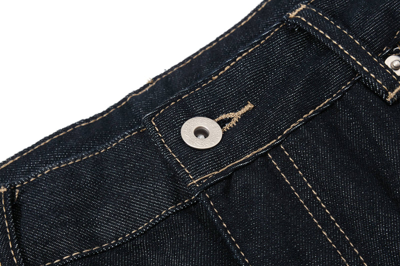 Close-up of the waistband button on dark wash denim pants with contrast stitching
