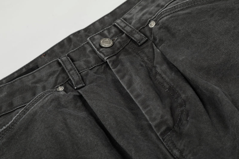 Close-up of the waistband and front pocket rivets on black washed denim cargo pants