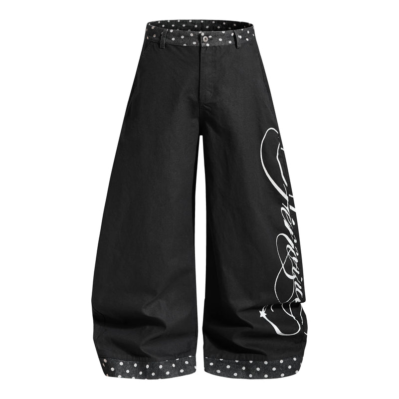 Black wide-leg denim jeans with white script print and polka dot waistband, front view