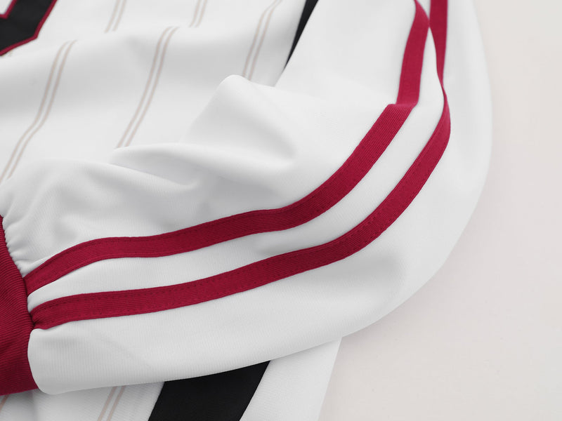 Close-up of white sleeve with maroon stripes and side seam on the jersey