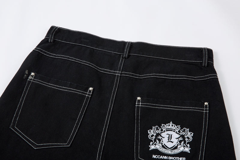 Back waist of black jeans with two patch pockets and embroidered crest on right pocket