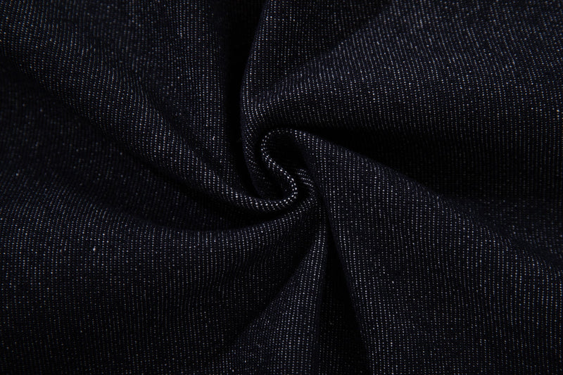 Close-up of dark indigo denim fabric with visible weave and draped folds