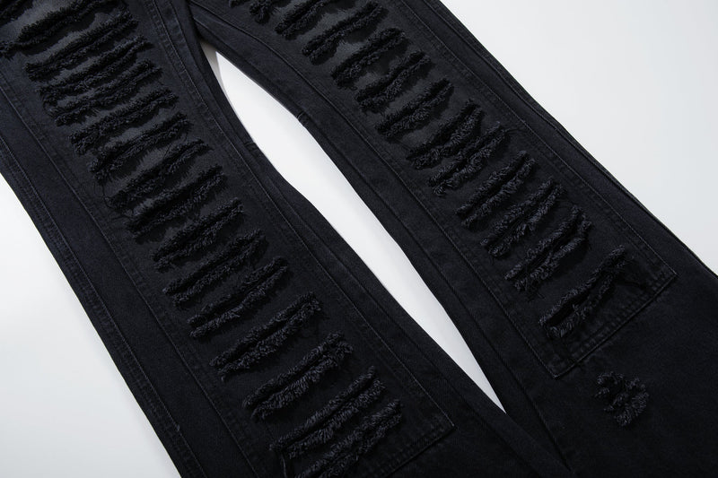 Close-up of shredded ribbed distressing along both legs of black jeans