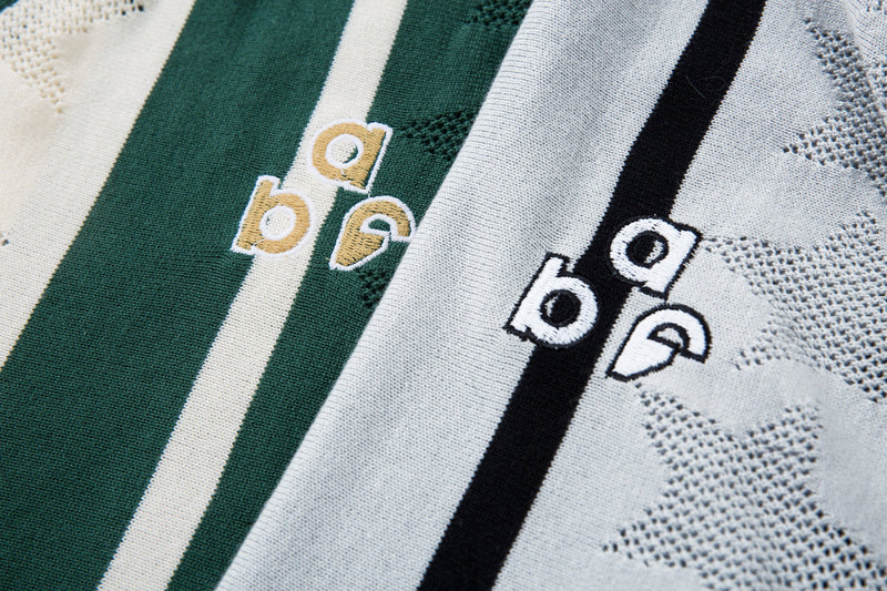 Close-up of chest embroidery on green and cream and black and gray striped knit polo shirts