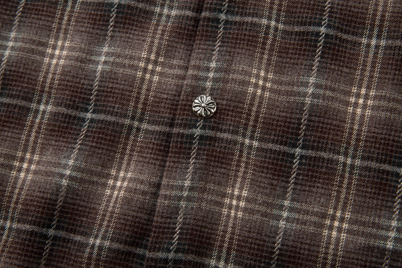 Close-up of a silver floral button on brown plaid fabric