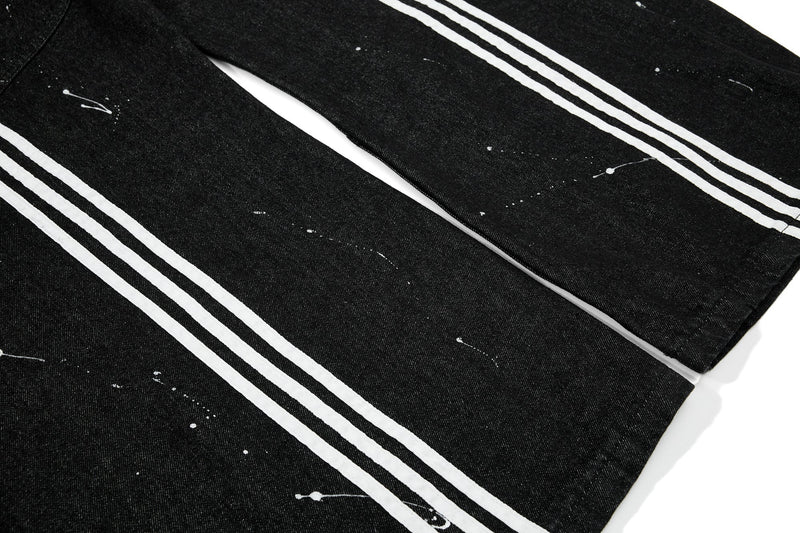 Black jeans legs with white triple side stripes and paint splatter, angled view