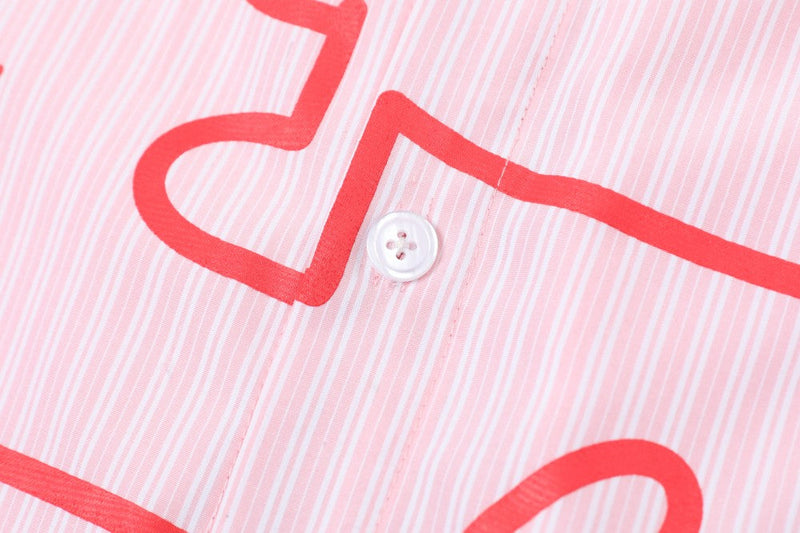 Close-up of pink striped shirt fabric with white button and red printed graphic