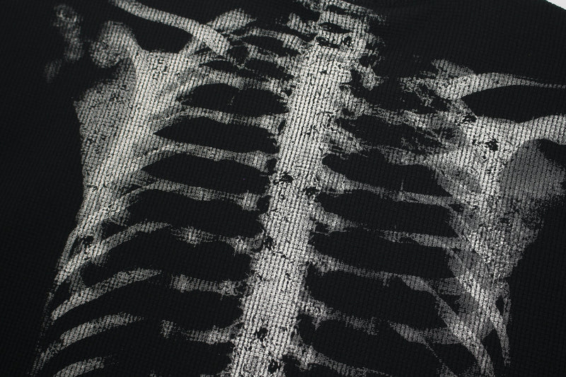 Close-up of black graphic tee with distressed white ribcage skeleton print and textured streetwear style