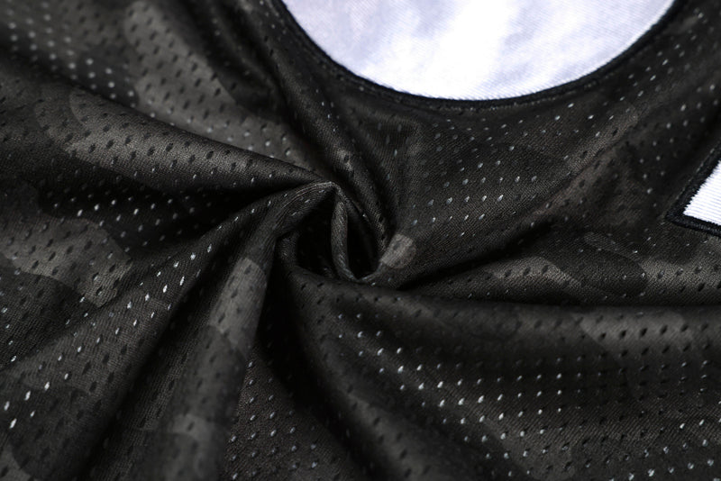 Close-up of dark camo mesh athletic jersey fabric with perforated texture and black football shirt details