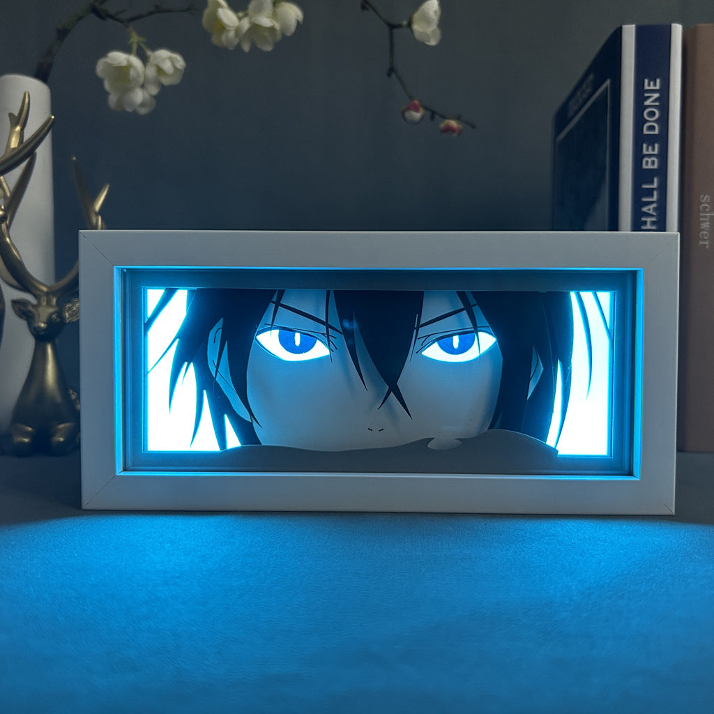 The Seakoff Noragami Anime Light Box – Yato 3D LED Lamp showcases a black-haired, blue-eyed character similar to Yato from Noragami. The piece includes an antler-like ornament and a partially visible book titled &quot;SHALL BE DONE,&quot; enhanced by its dynamic color-changing effects.