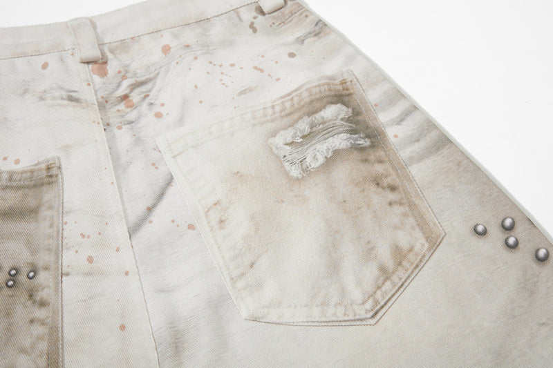 Back pocket close-up on cream jeans with distressed patch and splatter wash
