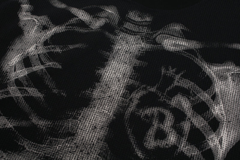 Close-up of black waffle-knit fabric with white skeleton x-ray print across the chest