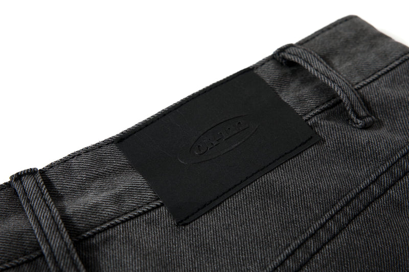 Close-up of black waistband patch label with stitched denim texture