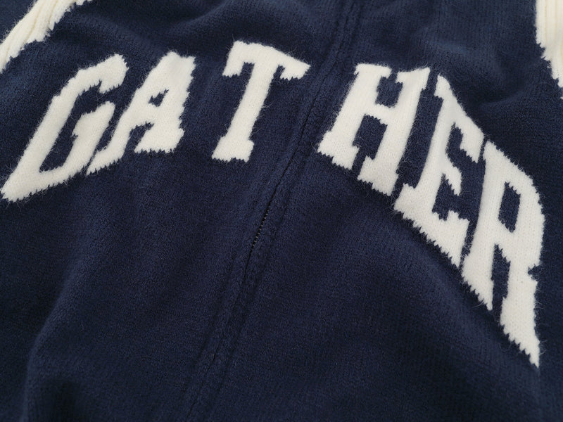 Close-up of GATHER lettering across the front of the navy knit jacket