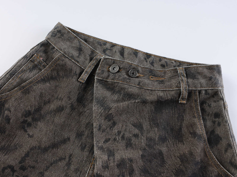 Close-up of the front waistband on dark patterned denim jeans with button closure and belt loops