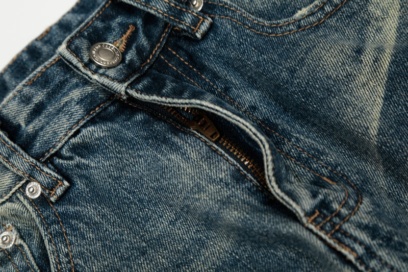 Close-up of the front fly and waistband on vintage washed distressed jeans