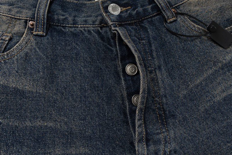 Close-up of the front waistband and button fly on faded blue denim jeans