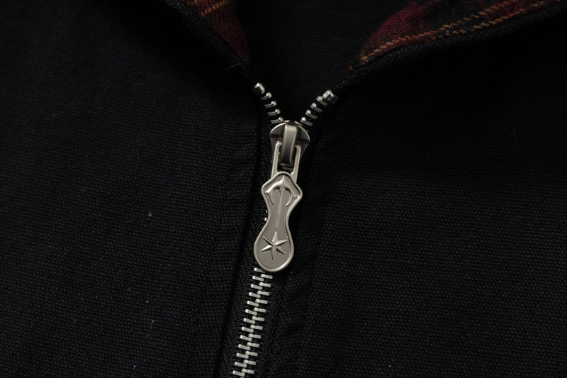 Close-up of silver zipper pull on black hoodie with plaid hood lining visible