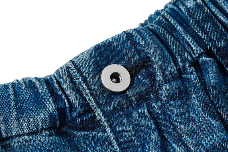 Close-up of waistband snap button and denim texture on washed blue camo jeans