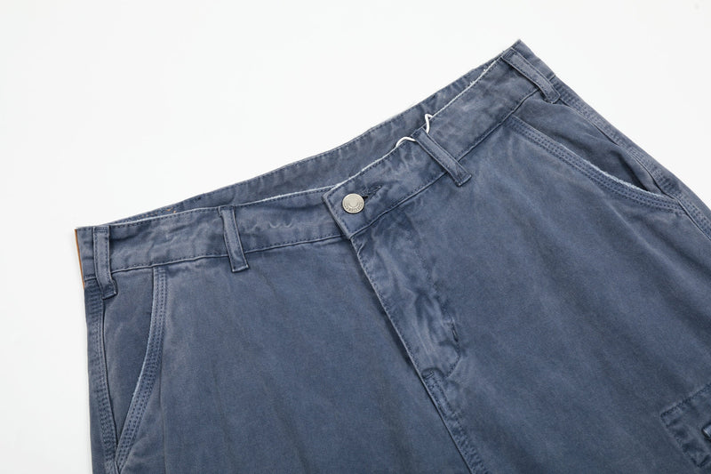 Close-up of washed blue cargo pants waistband with button, belt loops, and front fly