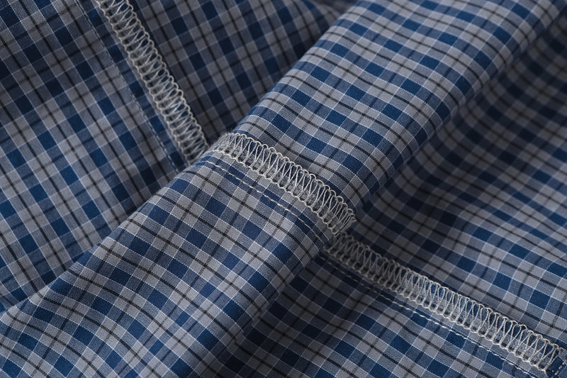Close-up of plaid sleeve seam with exposed white overlock stitching