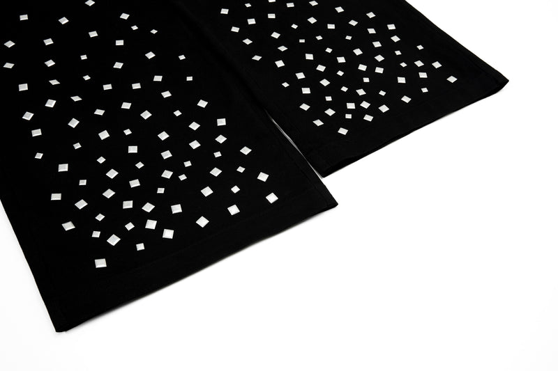 Close-up of black pant hem with silver square studs