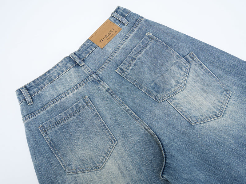 Close-up of the back waist on washed blue denim jeans with tan patch label and back pockets
