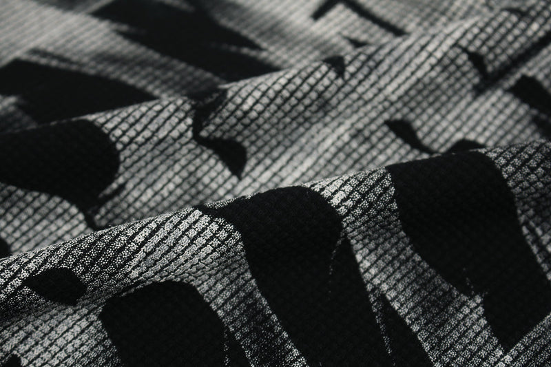 Close-up of black and white oversized tee fabric with a distressed skeleton graphic and mesh-like texture