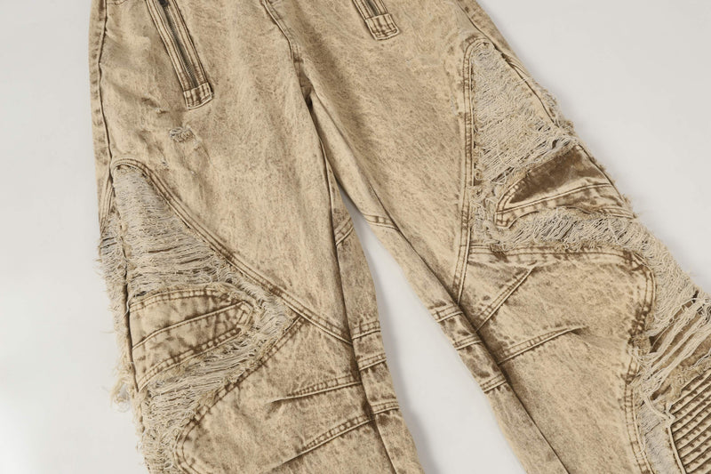 Front leg view of beige wide-leg jeans with frayed panel patches and zipper pockets