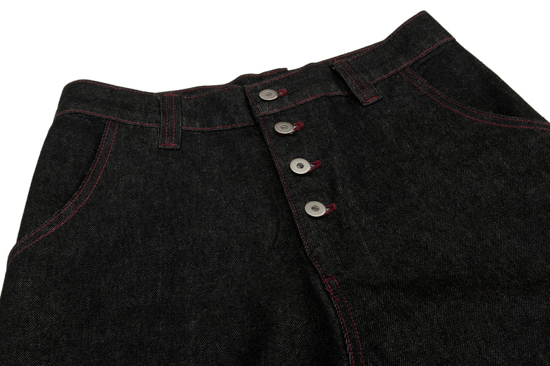 Close-up of black denim waistband and four-button fly with contrast red stitching