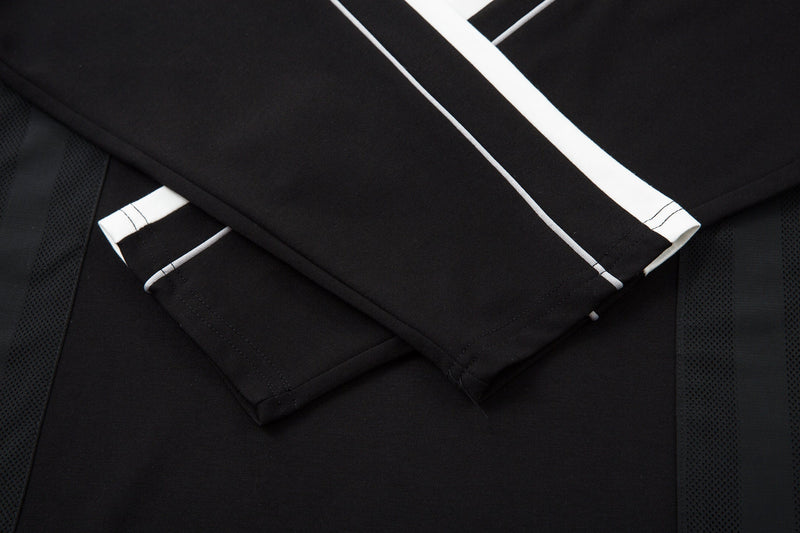 Crossed sleeve detail showing black top with white piping and mesh panels